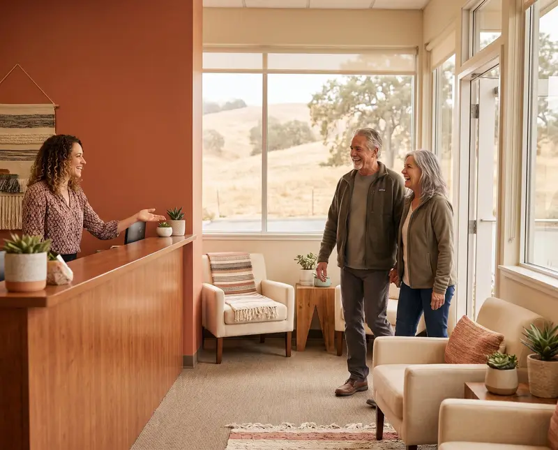 A friendly front-desk receptionist welcoming an older couple to our Madera clinic